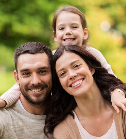 wife, husband, and child all smiling