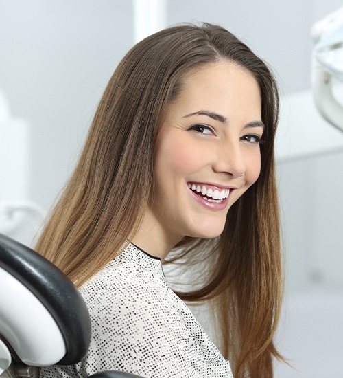 woman smiling over shoulder in dental exam chair