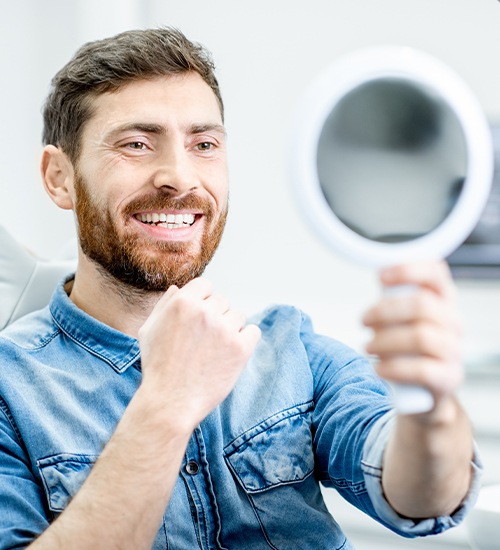 man with beard checking smile in circle mirror