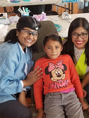 Dr. Kurian smiling with young female patient and her mother