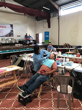 Dr. Kurian working on male patients smile while he leans back