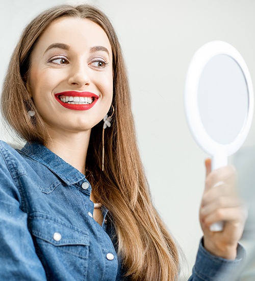 woman with red lipstick on checking smile in mirror