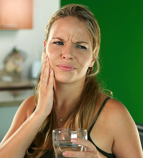 woman holding cheek in pain