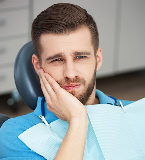 man holding cheek in pain