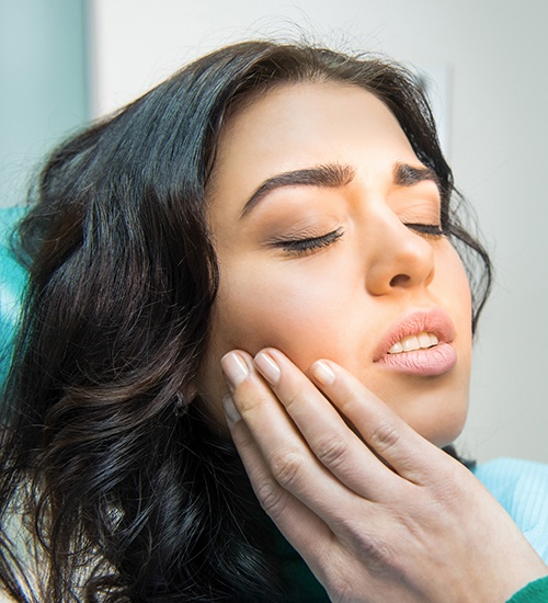 woman holding cheek with eye closed