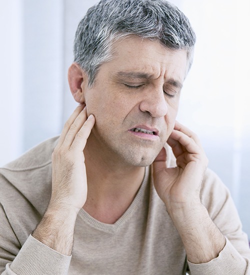 man holding jaw in pain